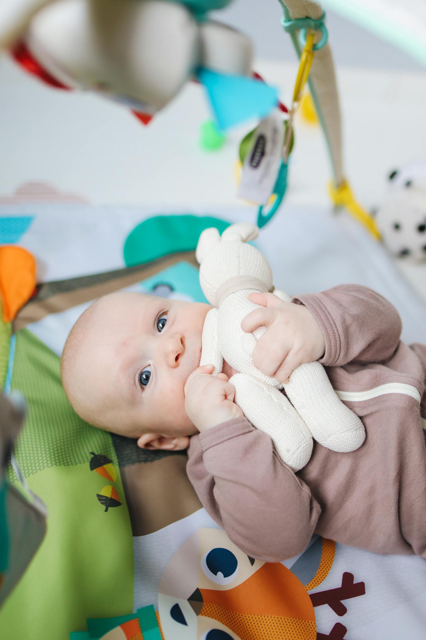 Cute baby enjoying playtime with a stuffed toy in a colorful indoor setting.
